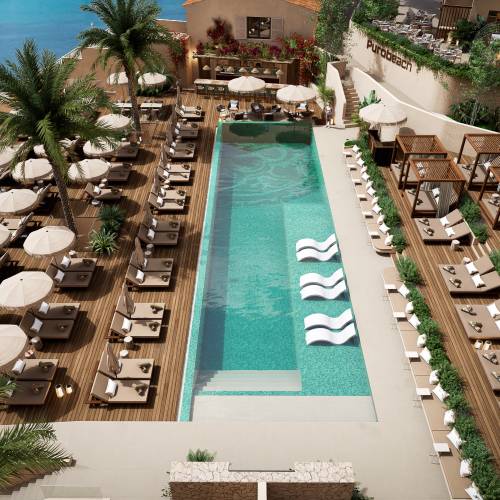 Hotelpool mit rechteckigem Becken, Liegest&uuml;hlen und Sonnenschirmen auf Holzdeck, Palmen und Meerblick im Hintergrund