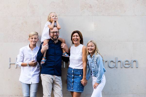 Eine Familie steht vor der Hotelanlage 'Storchen'. Der Mann tr&auml;gt ein Kind auf den Schultern, w&auml;hrend die anderen Familienmitglieder daneben stehen. Die Frau h&auml;lt die Hand eines M&auml;dchens.